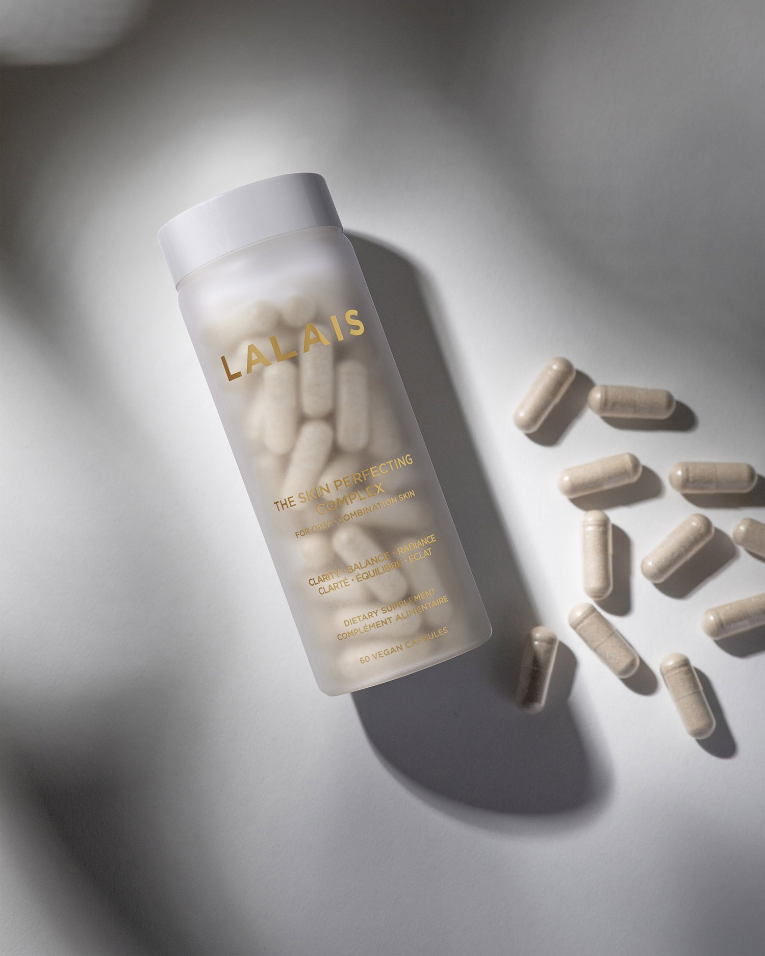 Lalais supplements in a clear bottle with loose capsules beside it.